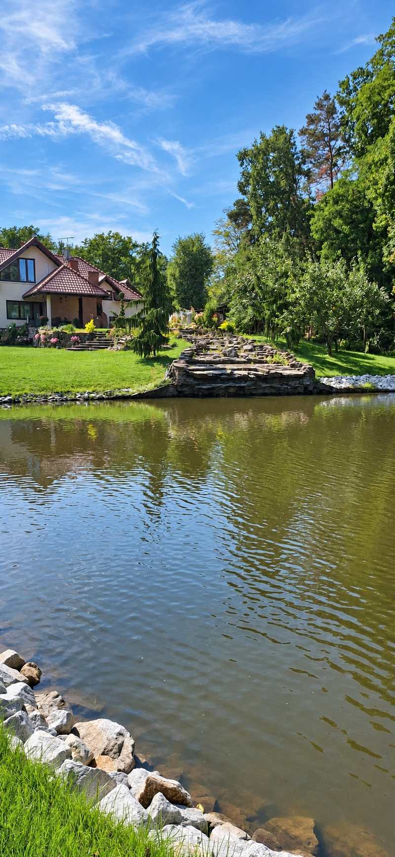 Ogród ze stawem i kamiennym obrzeżem